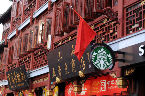 Shanghai, China - October 1, 2012: on China National Day of 2012, a Starbucks logo is seen outside a busy Starbucks store in a big shopping center -- Yuyuan Tourist Mart (AA<YaYaa Y). A red Chinese national flag is hanging above the logo, along with other Chinese store signs.
