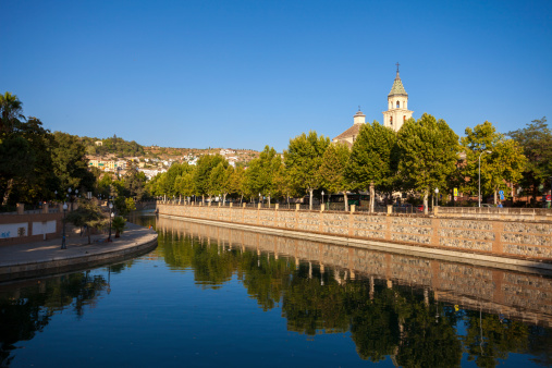 Granada, Spain - August 14, 2011: Late afternoon view of a church reflected on the Rio Genil, a river that runs through Granada in Spain. On close inspection, people can be seen in the background.