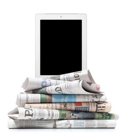 Milano - Italia - May 20, 2013: Photograph of a tablet on stack of newspapers taken in the studio. The newspapers are: The Daily Telegraph, Frankfurter Allgemeine Zeitung, Business, Le Monde, El Pais, Corriere della Sera, Il Sole 24 ore.