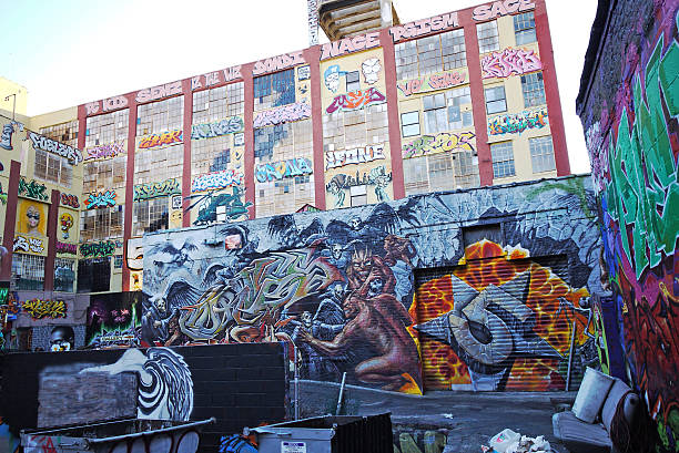 New York, NY, USA - October 31, 2013: Two New Yorkers, one with a halloween mask, walk east past the Bowery Mural Wall at the intersection of Bowery and Houston streets on the Lower East Side of Manhattan. The mural is a cooperative effort headed by the artist Swoon. Groundswell artists Yana Dimitrova, Angel Garcia, Jazmine Hayes, and Misha Tyutyunik also helped with the colorful creation which memorializes the ongoing healing and recovery efforts made in New York City communities among the neighborhoods affected by Hurricane Sandy in 2012. The mural was completed on October 29, the first anniversary of Superstorm Sandy.