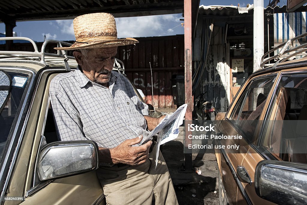 Taxi driver in Beirut. Beirut, Lebanon - September 9, 2009: Taxi driver in Beirut.A taxi driver in Beirut  waiting for the next customer is reading of crumpled newspaper pages. Beirut Stock Photo