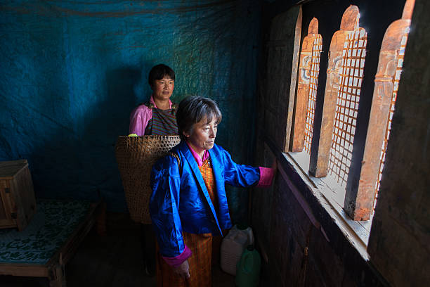 Due donne guardando bhutanesi Thangbi festività dall'interno di casa loro - foto stock