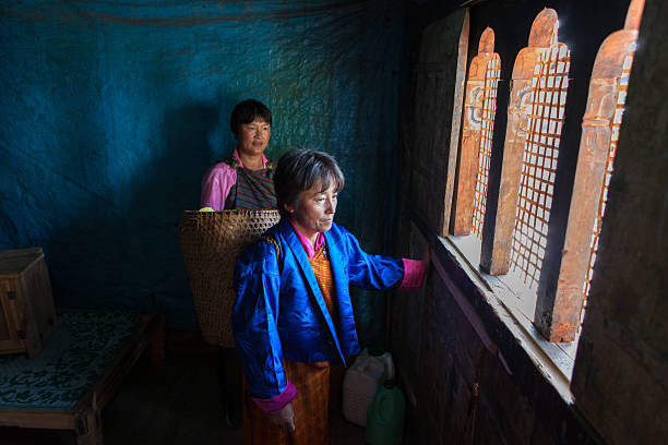 Two bhutanese women watching Thangbi festivities from inside their home stock photo
