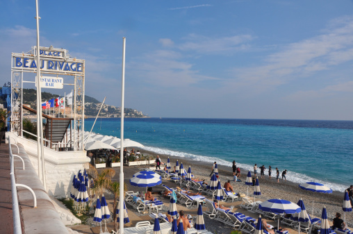 Nice, France - October 09, 2012: Beach 'Plage Beau Rivage' in front of the famous 5* Hotel 'Negresco', with people enjoying the autumn sun, on a weekday in Nice in October 2012.