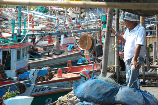 Hua Hin, Thailand - January 24, 2013: Thai fish dealer waiting for the catch at Khao Takiap fishing harbor.