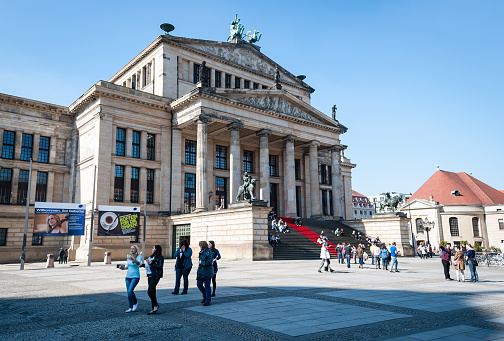 Berlin, Germany - March 23, 2012: People walking and looking around in Gendarmenmarkt square, Berlin. The image shows the Konzerthaus famous building. Sunny day.