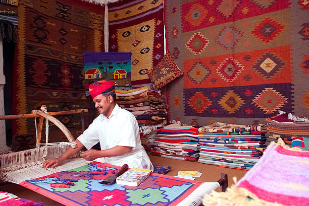 Carpet/tapestry weaving Jodhpur, India - February 28, 2013: A craftsman uses a handloom to produce rugs and tapestries.  The handloom sector is known for its heritage and the tradition of excellent craftsmanship of India. weaverbird photos stock pictures, royalty-free photos & images
