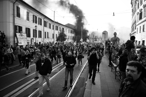 Rome, Italy - October 15, 2011: Hundreds of hooded demonstrators clashed with police in some of the worst violence in the Italian capital for years, setting cars on fire and breaking shop and bank windows. Police repeatedly fired tear gas and water cannons in attempts to disperse protesters but the clashes with hard-core demonstrators continued hours after tens of thousands of people in Rome joined a global day of rage against bankers and politicians.