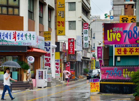Daejeon, Korea - July 4, 2013: man and woman walking down the street in rain.