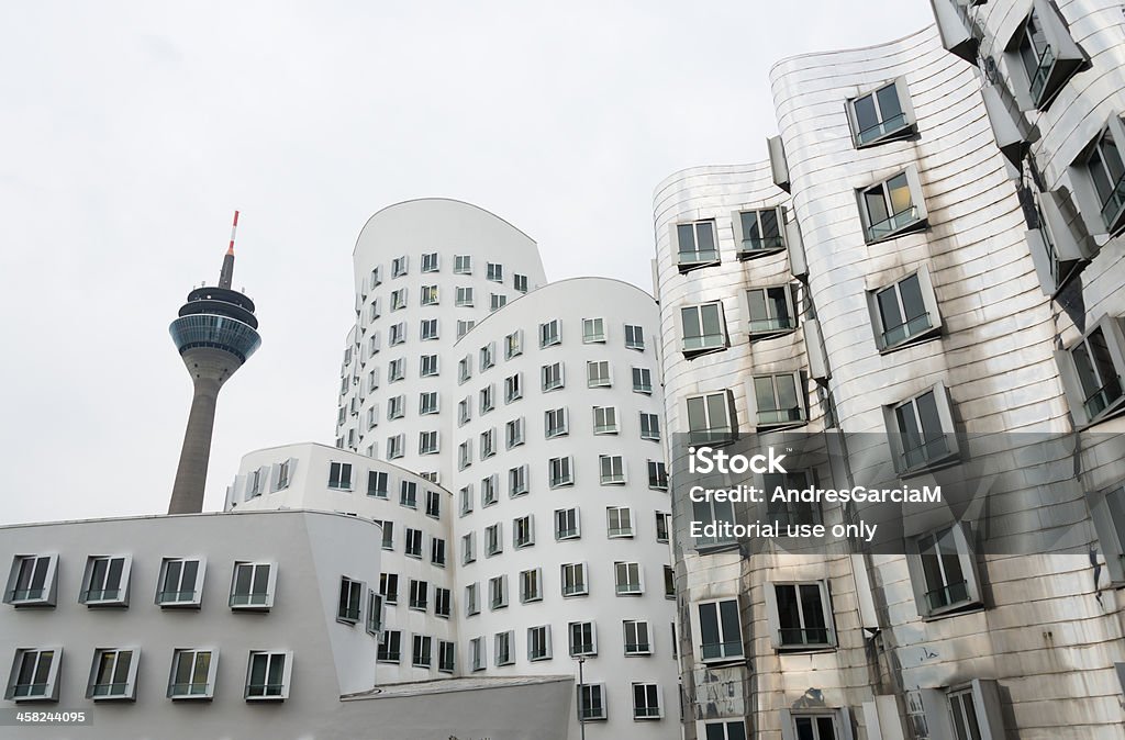 Neuer Zollhof buildings and Rhein Tower at MedienHafen, Dusseldorf Dusseldorf, Germany - March 8, 2013: View of Frank Gehry's famous distorted buildings and television tower in the background in DAsseldorf, Germany. The building complex consists of three separate buildings, and was completed in 1998. Neuer Zollhof Stock Photo