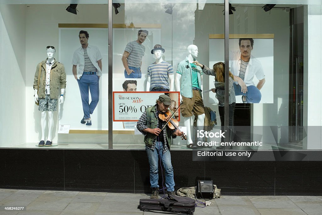 Busker davanti a un high street Shopping finestra. - Foto stock royalty-free di Abbigliamento