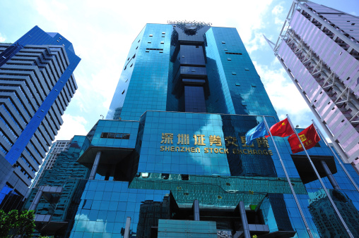 Shenzhen city,China - July 11,2012: Waving flags in front of the Building of Shenzhen Stock Exchange, Shenzhen city,Guangdong province,China