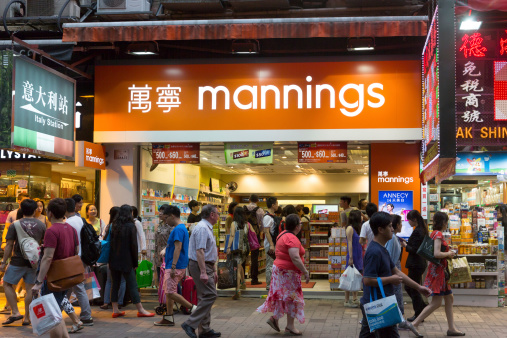 Hong Kong, China - August 17, 2013: People walk past Mannings Store in Haiphong Road, Tsim Sha Tsui, Kowloon, Hong Kong. It is a chain of personal health and beauty retailer in Hong Kong. It offering wide range of pharmacies, healthcare, personal care and skin care products. Many people are inside the store.