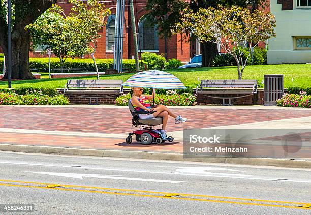 Attracive Lady Rides In Her Electric Wheelchair With A Parasol Stock Photo - Download Image Now