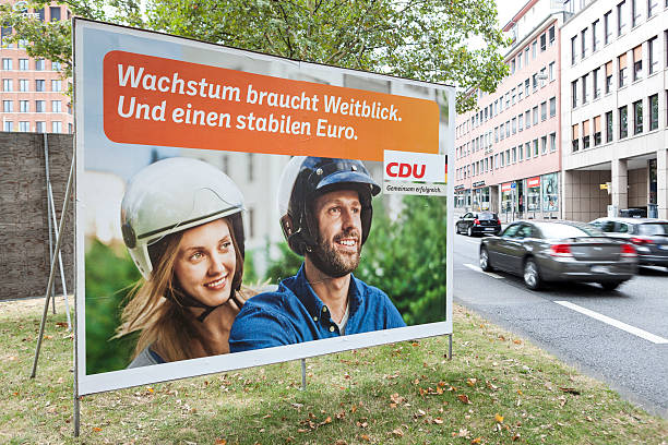 Election campaign billboard of CDU / Bundestagswahlkampf 2013 Wiesbaden, Germany - August 9, 2013: Election campaign billboard of the German Christian Democrats (CDU) in the city center of Wiesbaden. Germany faces federal elections scheduled for September 22. Some passersby and road users in the background. german federal elections photos stock pictures, royalty-free photos & images
