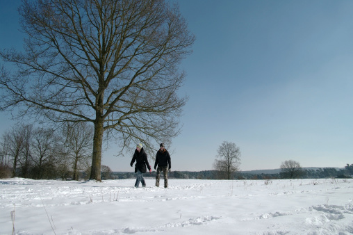 Brunssum, the Netherlands - March 13, 2013 : A young couple is walking in the winter sun on a cold day in march. They enjoy the landscape very much on this late winter day in Limburg.
