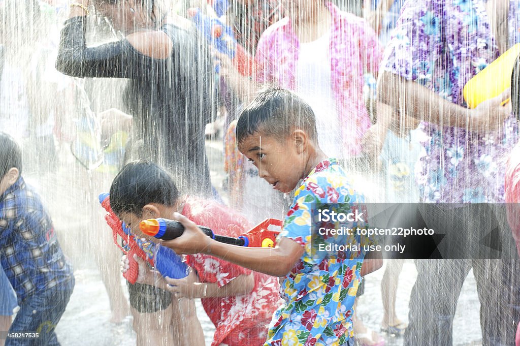 Child playing water festival in Thailand. Ayuttaya, Thailand - April 13,2012: Boy with gun shoot water into the plastic to play Songkran Festival ( water festival ) is celebrated in a traditional New Year's Day from April 13 to 15, with the splashing water and dancing on April 13, 2012 in Ayuttaya, Thailand. Adult Stock Photo