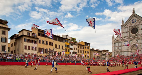 Florence, Italy, June 18, 2011: In the historic Piazza Santa Croce, on the background of Basilica, is about to begin the game of Calcio Storico Fiorentino. The flag bearers in traditional costumes, perform in front of thousands of spectators.