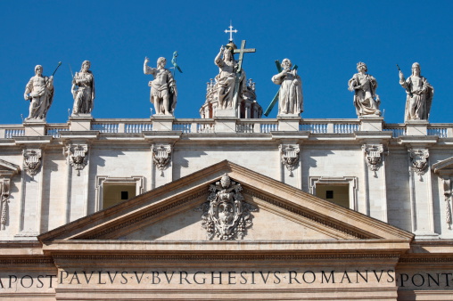 Vatican, Vatican City State - February 24, 2012: Statues of Christ, John the Baptist, and some apostles carved by Michelangelo on the top of Saint Peter Basilica facade.