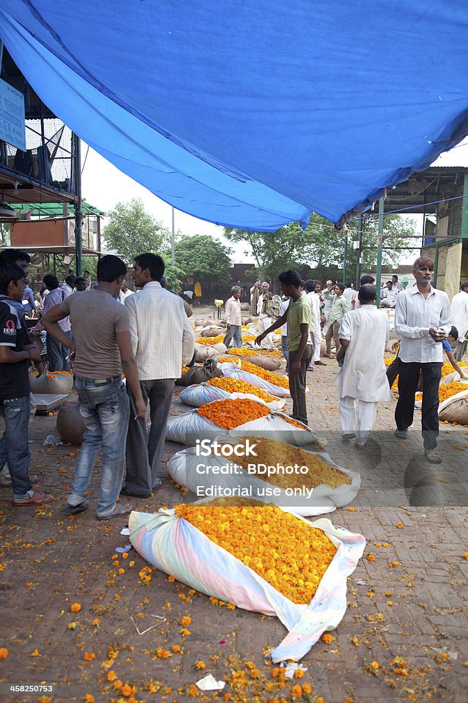 Wholesale flower market, New Delhi New Delhi, India - July 6, 2013.  Commercial buyers and sellers discuss prices of marigolds at the flower market.  Each sack weighs approximately 25 kgs and costs the equivalent of 19 US Dollars. Buying Stock Photo