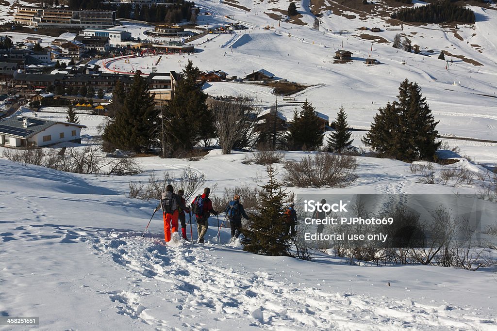 Seiser Alm (Dolomites) - Group of people with snowshoes Seiser Alm, Dolomites, Italy - March 1, 2011: Seiser Alm (Siusi Alp Dolomites) - Group of people with snowshoes walking on the snow . In background Compatch village with many hotels Dolomites Stock Photo