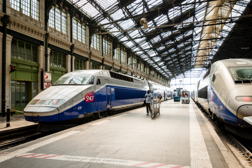 Paris, France - July 12, 2013: High speed TGV trains parked at the Gare de Lyon train station with passengers walking on the platform between the trains.