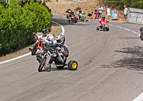 Predappio Alta, FC, Italy - July 28, 2012: tricycle drivers engaged in downhill performance of trike slide in a public road on the hill, during the european championship speed down