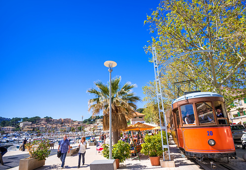 Port de Soller, Majorca, Spain - April 13, 2013: Tourist riding the historic tram from the Port of Soller to the town of Soller and enjoying a leisure walk at the Promenade and Marina of the popular Majorcian travel destination. 