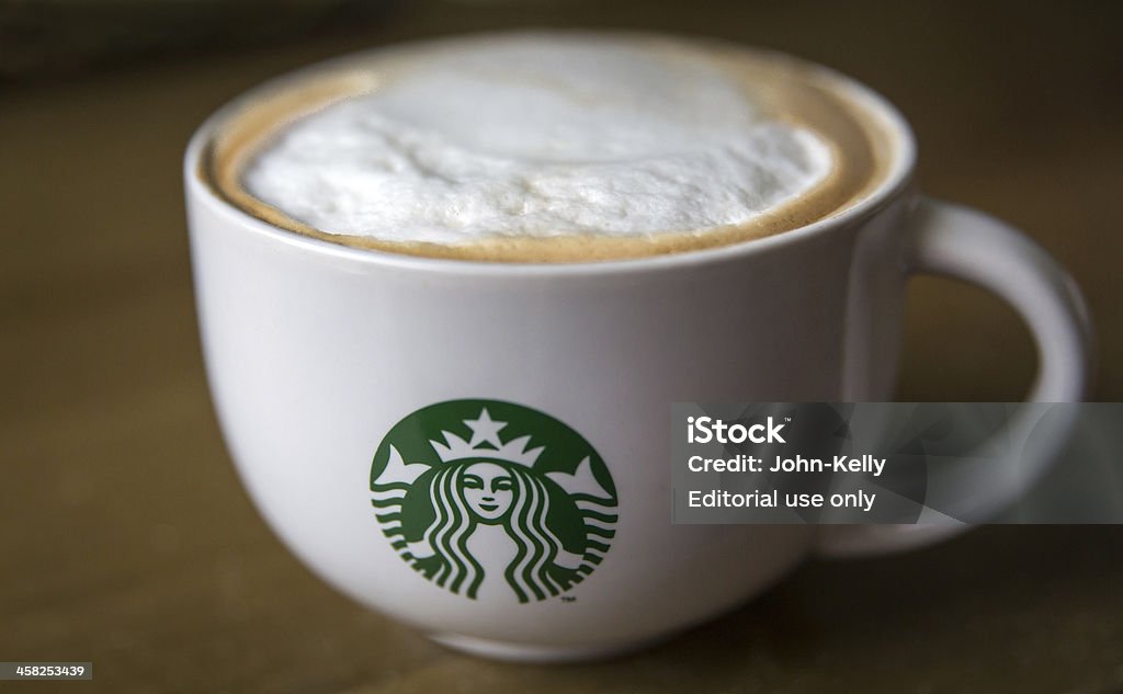 Starbucks Coffee Mug London, England - October 2, 2013: Close up of a Starbucks branded Cappucino Mug on a brown table. Starbucks Stock Photo