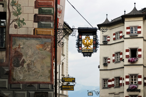 Innsbruck, Tirol - August 30, 2012: Innsbruck is the state capital of Tyrol. In the old town there are old buildings and hotels. The picture shows the coat of arms of the hotel golden eagle is seen. The facade is decorated with frescoes and on the right side picture is another hotel with red shutters.