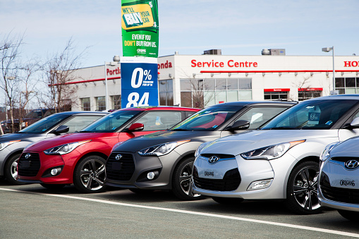 Dartmouth, Nova Scotia, Canada - April 18, 2013: Various colors of new Hyundai Veloster vehicles sit in a row on a car dealership lot displaying the front fascia of the vehicles.  Signage and dealership establishment are visible in background.  The Hyundai Veloster is a hatchback vehicle manufactured by Hyundai.  There is both a Veloster and Veloster Turbo which are both visible in row.