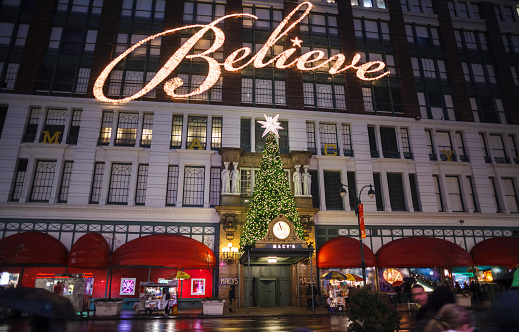 New York, New York, USA - December 9, 2012: An evening photo of the 34th Street exterior of Macy's Herald Square flagship store decorated for the Christmas Holiday Season. People can be seen on the street. The large illuminated \