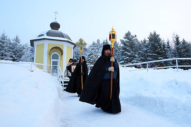 Tikhvin, Antoniyevo-Dymsky monastery, Russia, - January 19,2013.Monks of Russian Orthodox Church with subjects of a Christian cult go Religious procession. The procession comes to lake ice to consecrate water in an ice-hole.Traditional orthodox ceremony of the Epiphany after which believing pilgrims Christians are dipped into the consecrated ice water of the lake.Every year in day of January 19 orthodox Christians celebrate the Epiphany, bathing in an ice ice-hole.On a background chapel of an orthodox monastery.
