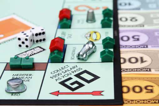 West Palm Beach, USA - August 15, 2013: A partial view of a Monopoly game board showing the Go start square with various game pieces placed on the board. Monopoly money in various denominations can be seen along one edge of the board.  Monopoly is a popular board game that is owned and distributed by Hasbro.
