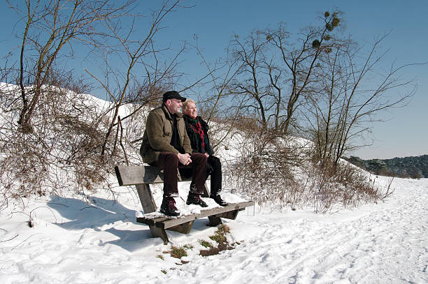 Brunssum, the Netherlands - March 13, 2013 : A senir couple is sitting in the winter sun after extreme snowfall in the late winter. The sun is very intensive in this time of yaer, the after winter in Limburg and we are waiting for spring.