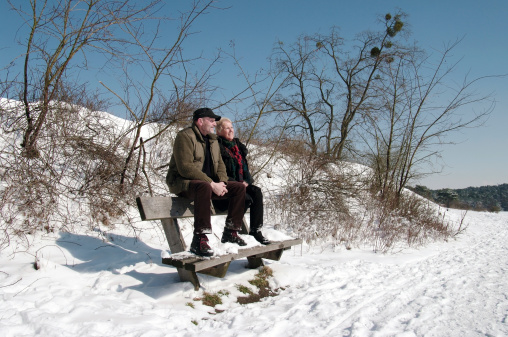 Brunssum, the Netherlands - March 13, 2013 : A senir couple is sitting in the winter sun after extreme snowfall in the late winter. The sun is very intensive in this time of yaer, the after winter in Limburg and we are waiting for spring.