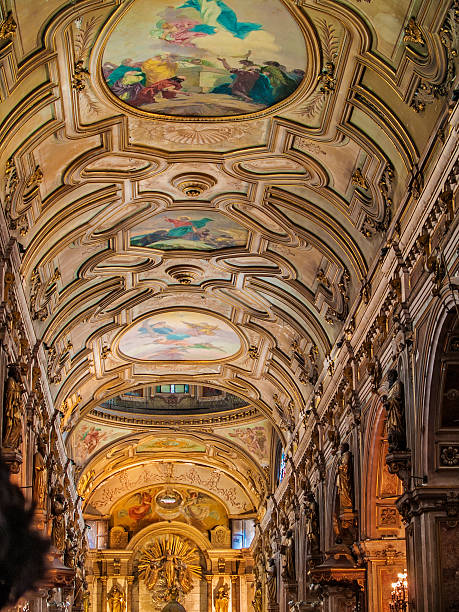 Interior view of a lavish church ceiling adorned with detailed frescoes, gold accents, and architectural symmetry, exuding religious grandeur.  \nBasilica of Sant'Andrea della Valle in Rome, Italy.