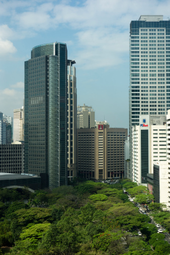 Manila, Philippines - February 5, 2013: Office view from the 14th level in a building in the financial district of Makati City. The peaceful and green Ayala triangle surrounded by skyscrapers and traffic.