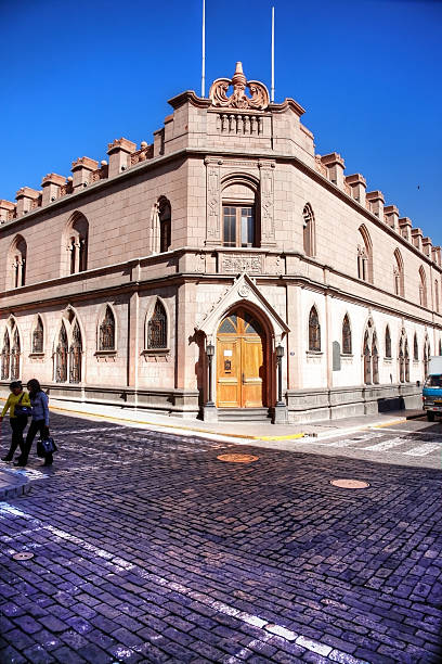 Arequipa, Peru - May 25, 2013: Peruvian arcitecture building on corner of cobblestoned street in the city of Arequipa. People are pictured crossing the road