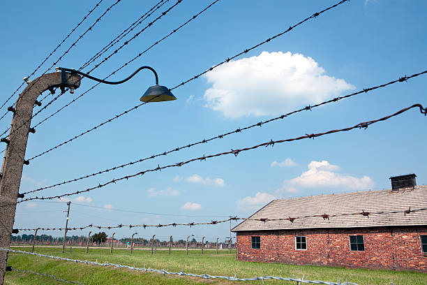 Auschwitz, Poland, July 6th, 2012: Prisoner barracks, with barb-wired fence focused in first term. Seen in Auschtwitz I nazi concentration camp,in Oswieciw, Cracow area, Poland.