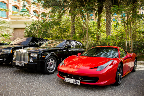 Dubai,  Arab Emirates - March 11, 2012: Ferrary 458 Italia and Rolls Royce Phantom luxury cars staying near Atlantis The Palm hotel