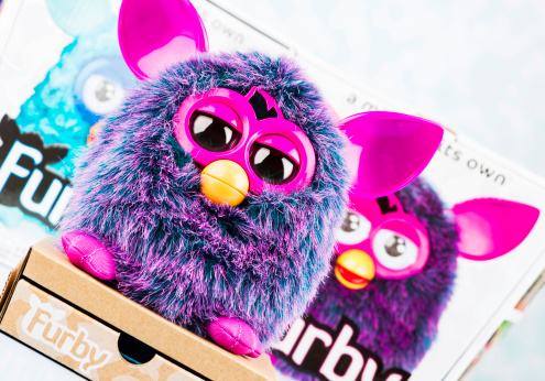 Suffolk, Virginia, USA - November 14, 2012: A horizontal studio shot of a purple Furby toy standing in front of its original packaging and the package of a teal-colored Furby. Furbys are a battery operated electronic toy, made by Hasbro that perform various moves and communicates in a 
