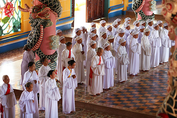 женщины верующих, молиться в храм в cao dai, вьетнам - caodaiism стоковые фото и изображения