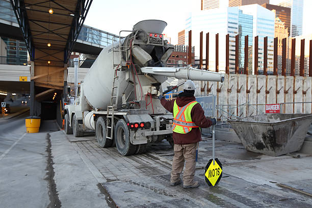 Construction Site Toronto, Ontario, Canada - February 6, 2012: Construction site in Downtown Toronto with a construction worker holding "Slow" sing directing traffic around the site construction skyscraper machine industry stock pictures, royalty-free photos & images