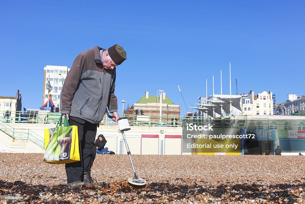 Old man and metal detector Brighton, UK - February 8, 2011: Old man looking for metal objects on the beach with a metal detector on February 8, 2011 in Brighton, UK. There are an estimated 2 million pensioners living below the breadline. Poverty Stock Photo