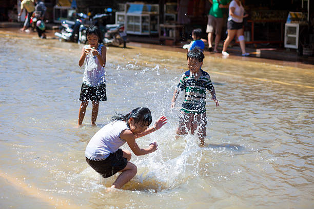 bambini giocano in floodwaters, siem reap, cambogia - floodwaters foto e immagini stock