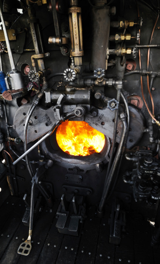 Silverton, United States - June 16, 2013: On the footplate of locomotive No. 482 of the Durango and Silverton Narrow Gauge Railroad at Silverton, Colorado, USA. The firebox doors are open, waiting for another shovelful of coal. No, 482 is one of the K-36 class Mikado 2-8-2 steam locomotives designed for the D&RGW (Denver & Rio Grande Western) and built by the Baldwin Locomotive Works in 1925. It hauls steam trains over the railroad which now operates as a tourist attraction carrying passengers over the 45 miles of 3 ft gauge track between Silverton and Durango.