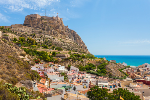 Alicante, Spain - August 19, 2011: View of the coastal city of Alicante with the Santa Barbara Castle overlooking the coastline and some local buildings below.