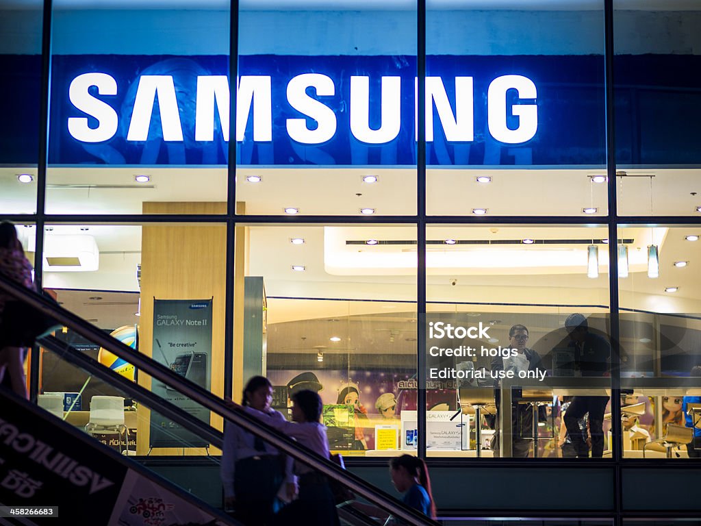 Samsung store, Bangkok Bangkok, Thailand - November 1, 2012: Exterior view of a Samsung shop in the Siam Square area of Bangkok at night. people can be seen inside the store and making their way up an escalator outside. Image captured from the public walkway. Samsung Stock Photo