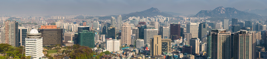 Seoul, Korea - 30th April 2013: Aerial panoramic vista across the skyscrapers and landmarks, mountain parks and crowded suburbs of central Seoul, South Korea. Composite panoramic image created from ten contemporaneous sequential photographs.